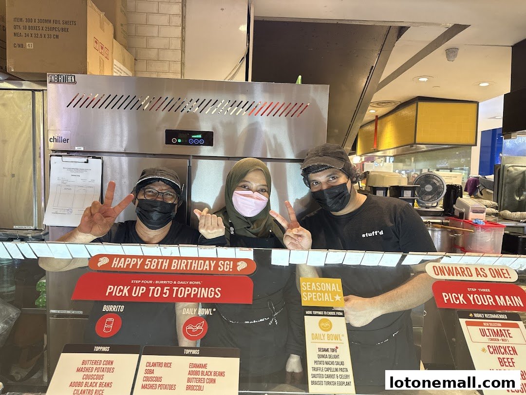 Three smiling staff members at Stuff'd, holding up peace signs and showing off their toppings.