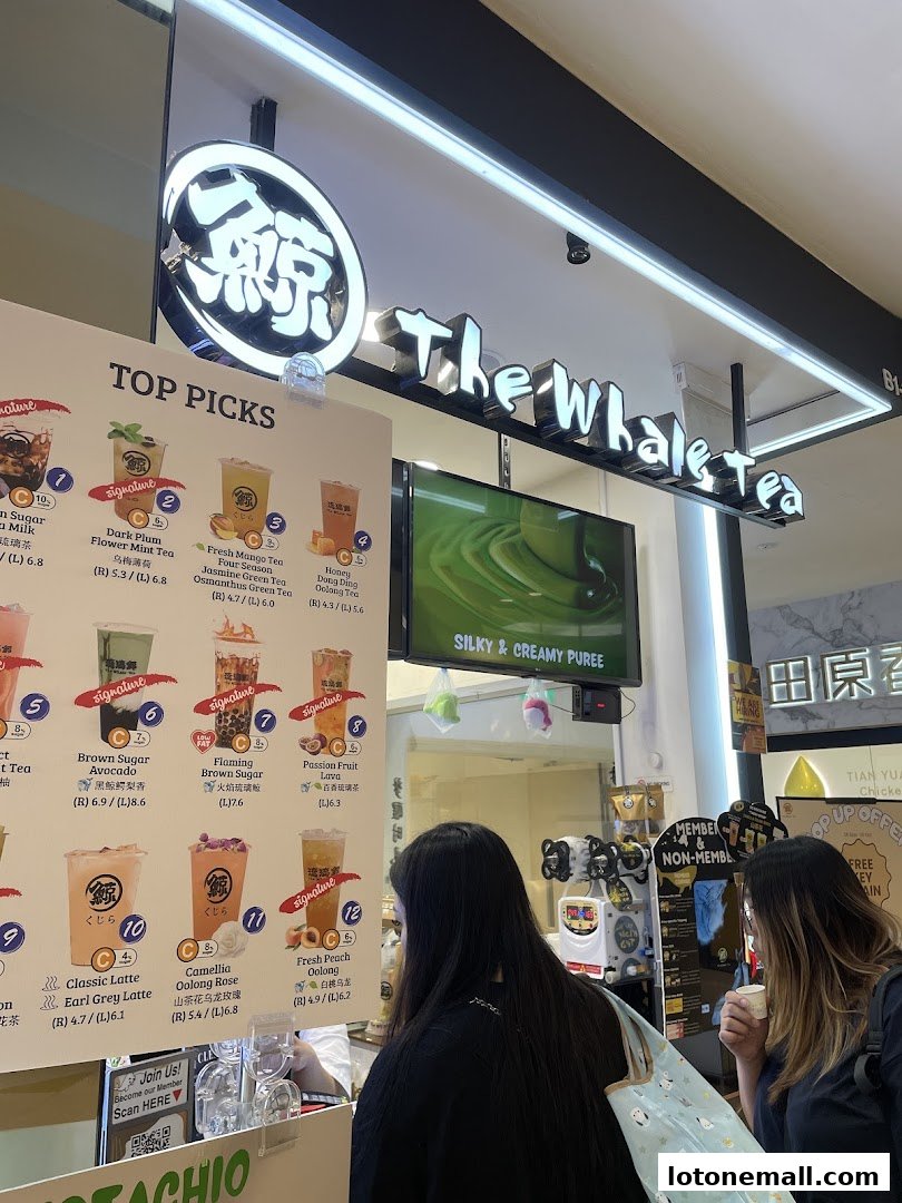 Customers ordering at The Whale Tea SG, with a menu board displaying popular drinks.