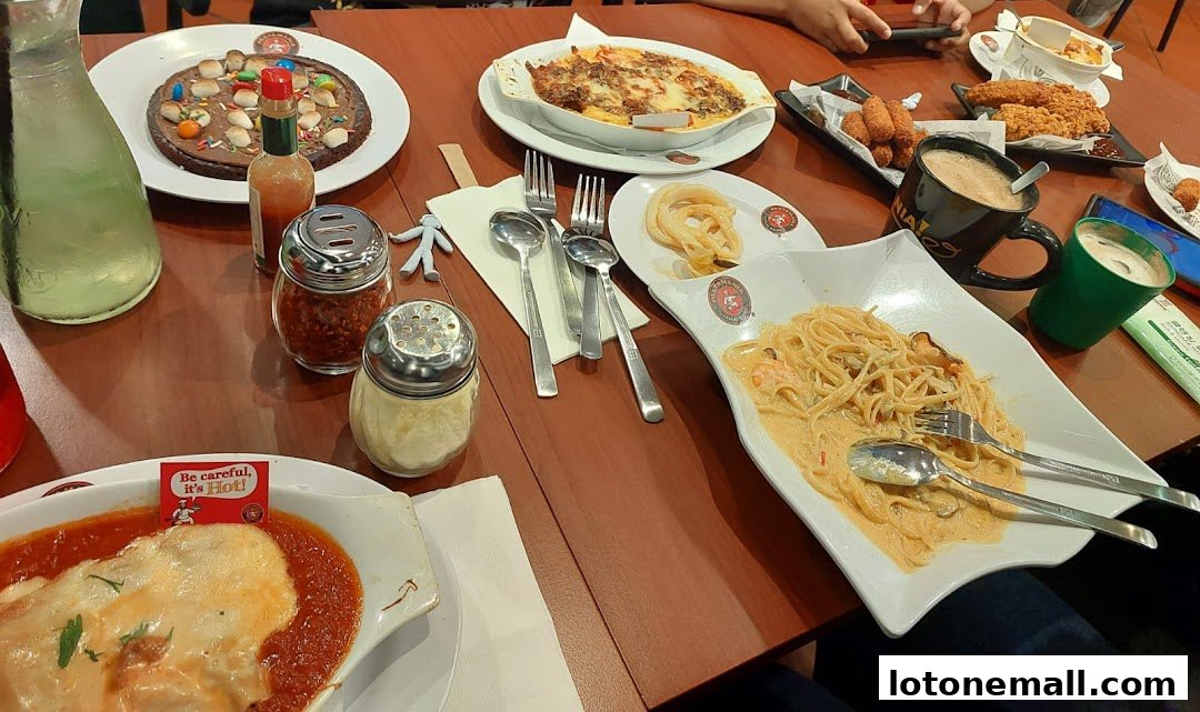 A table laden with various Italian dishes, including pasta, baked pasta, and fried items, with drinks.