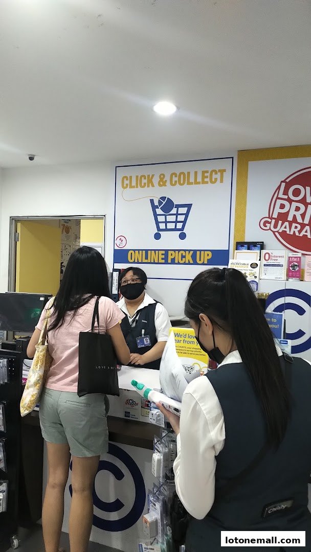 Customers at a counter with a "Click & Collect" sign and staff assisting.