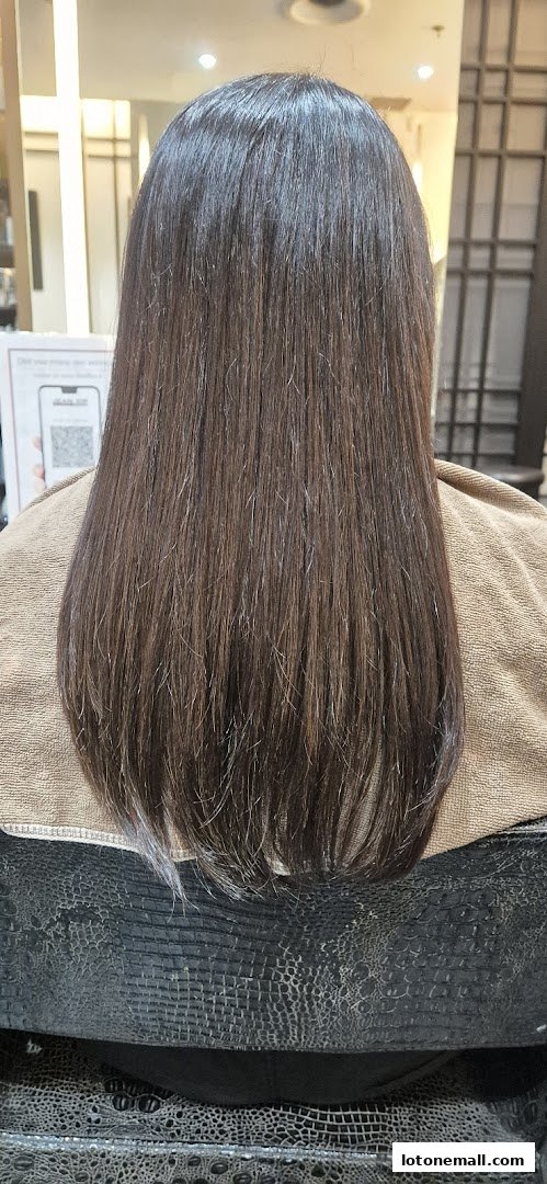 A person's long, dark brown hair is shown from the back, styled straight.