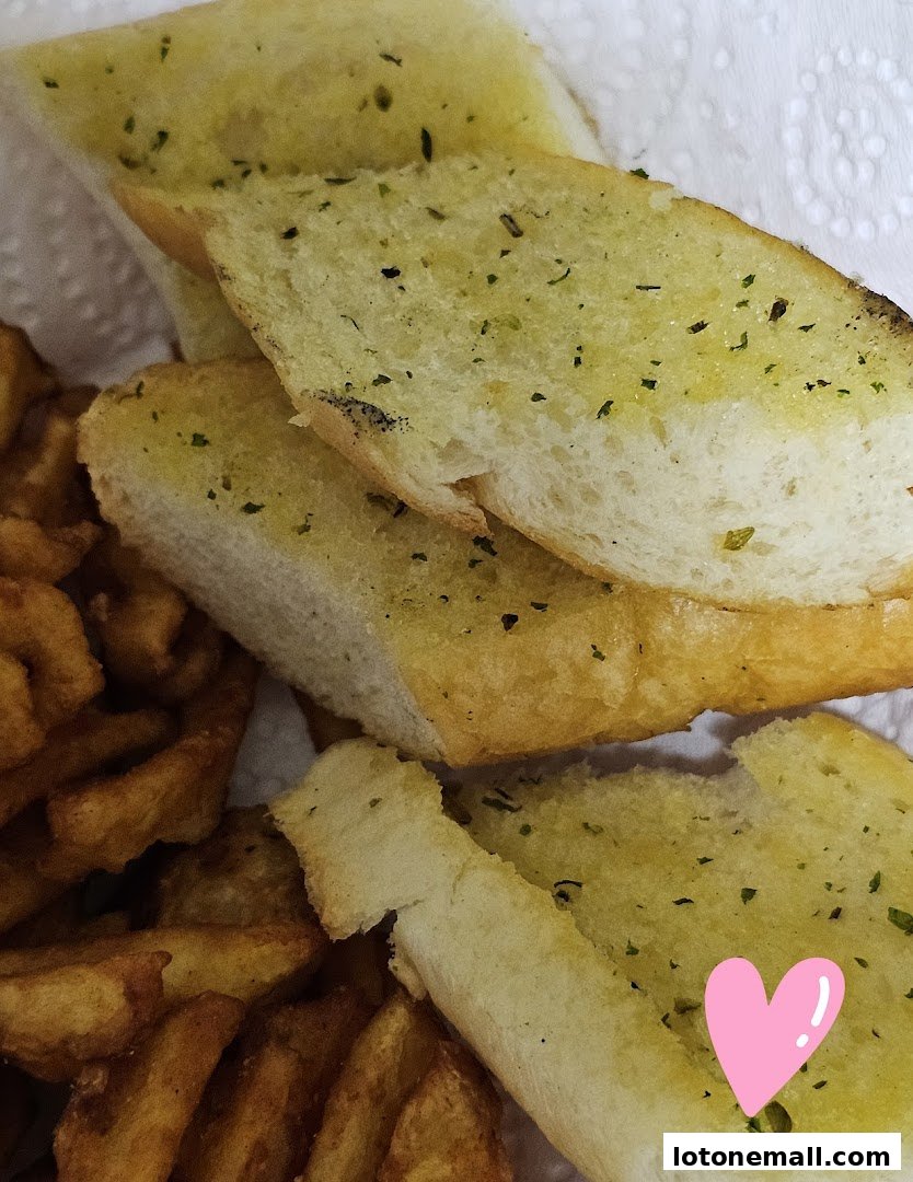 Close-up of garlic bread slices and crispy fries, with a pink heart sticker.