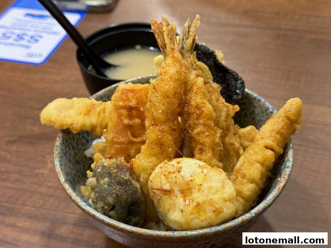 A close-up of a delicious tempura bowl with shrimp and vegetables, served with miso soup.