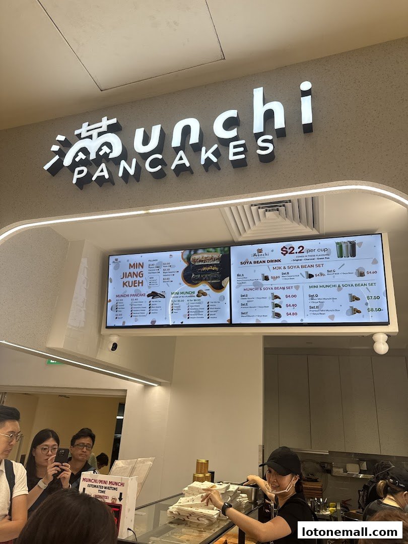 The Munchi Pancakes shop front with a menu board and staff serving customers.