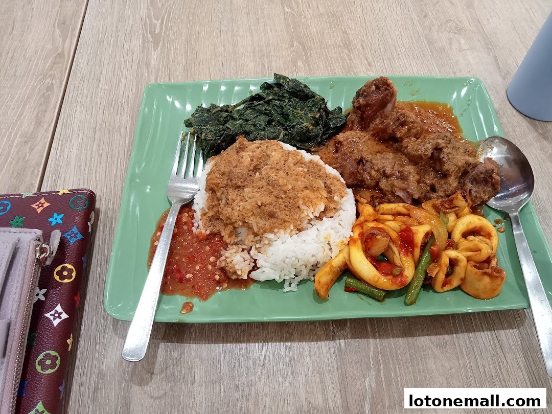 A plate of rice with various side dishes, including meat, vegetables, and squid, served at a food court.