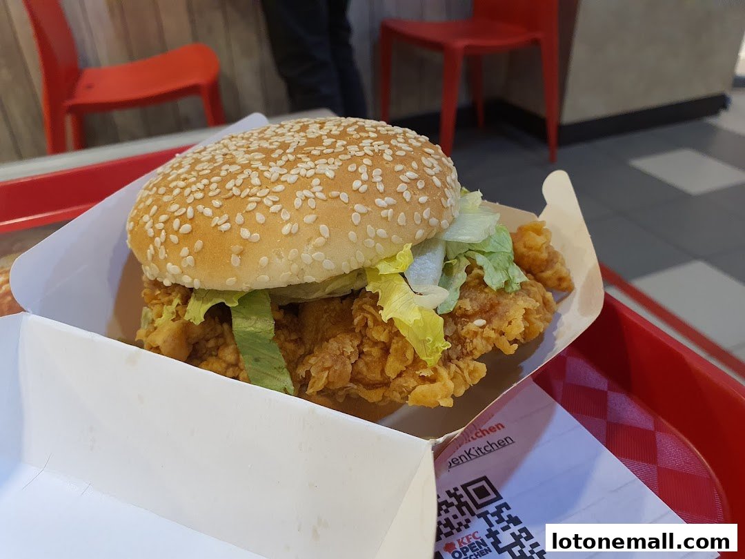 A close-up of a delicious KFC chicken burger with lettuce in a white box.