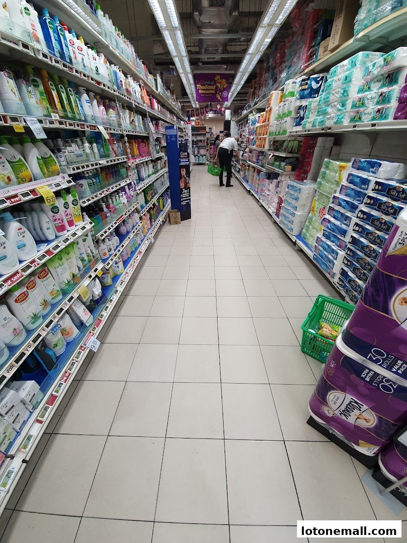 Aisle in a supermarket with shelves stocked with toiletries and household items.