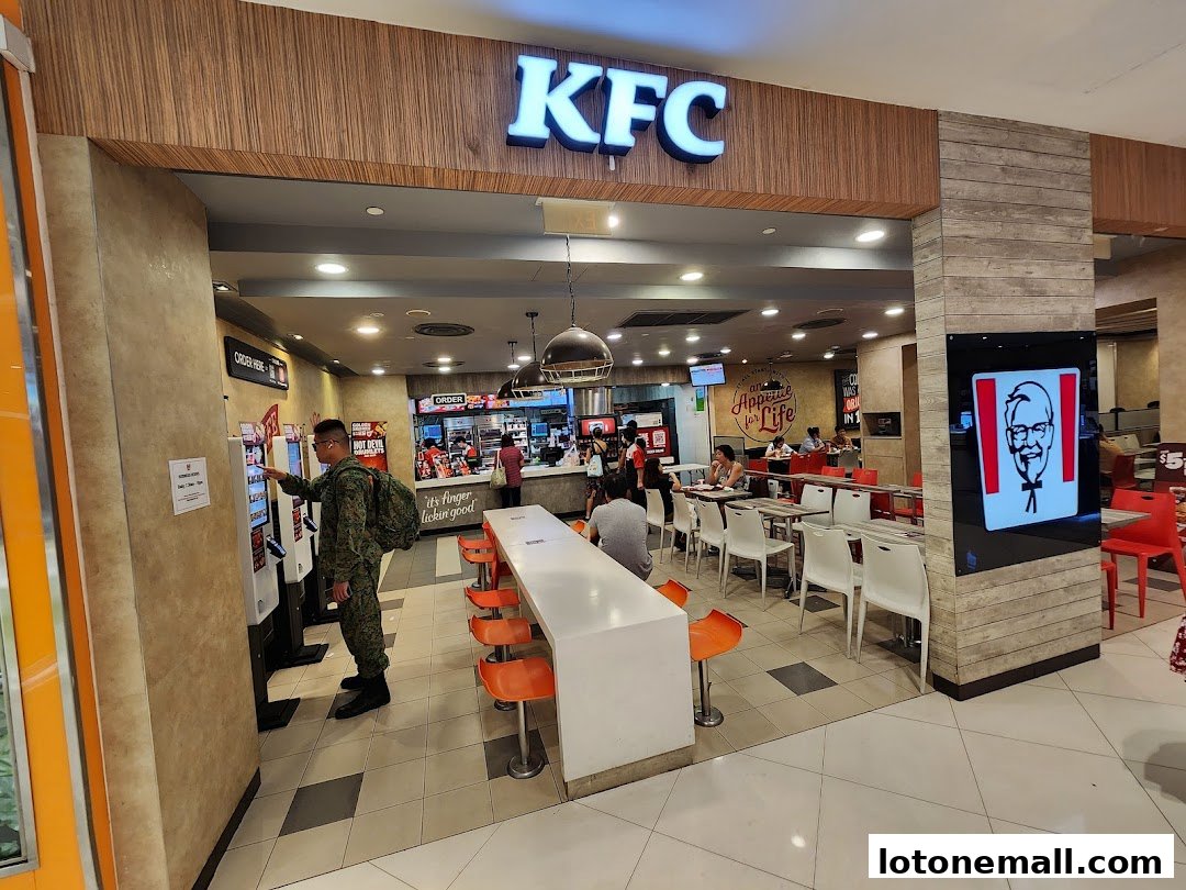 KFC restaurant interior with customers ordering and dining, featuring the iconic Colonel Sanders logo.