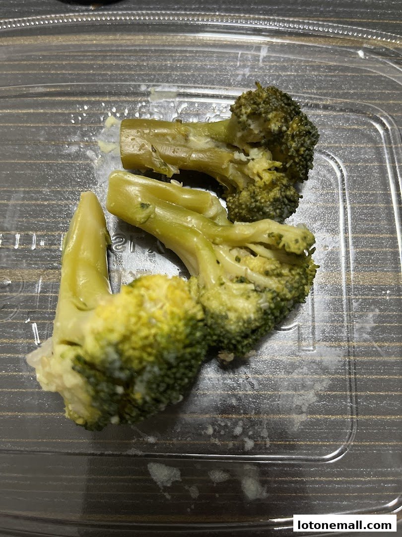 Steamed broccoli florets and stems in a clear plastic container.