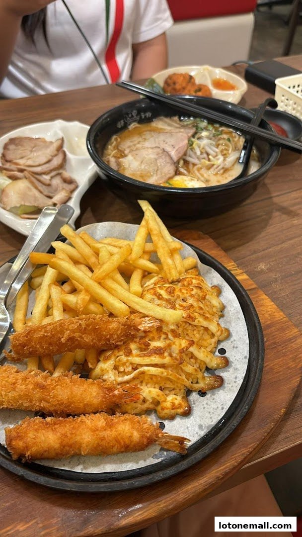 A table with ramen, fried shrimp, fries, and sliced pork at Ajisen Ramen.