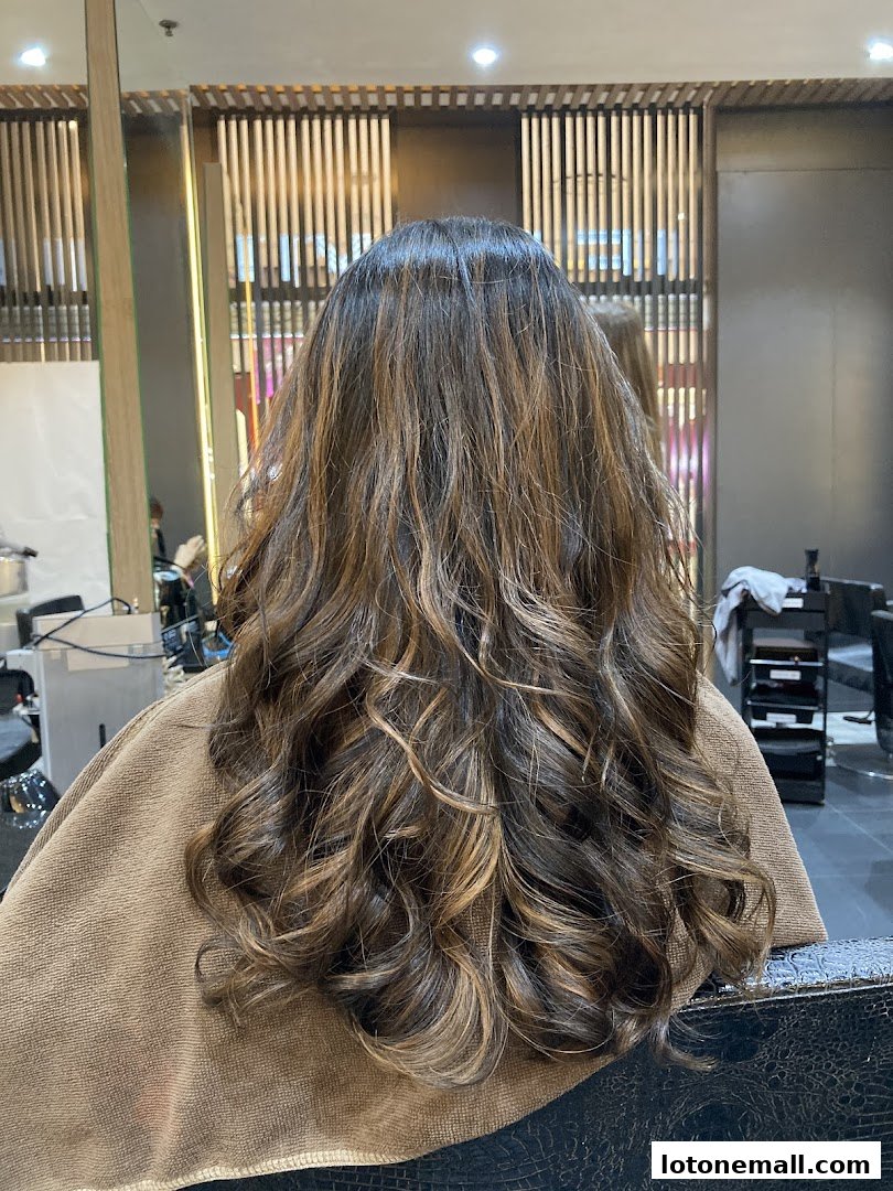 A person's back with beautifully styled, highlighted, and curled hair.