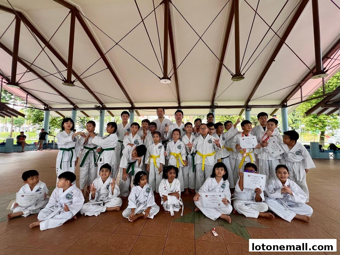 A group of children and adults in martial arts uniforms pose for a photo, some holding certificates.