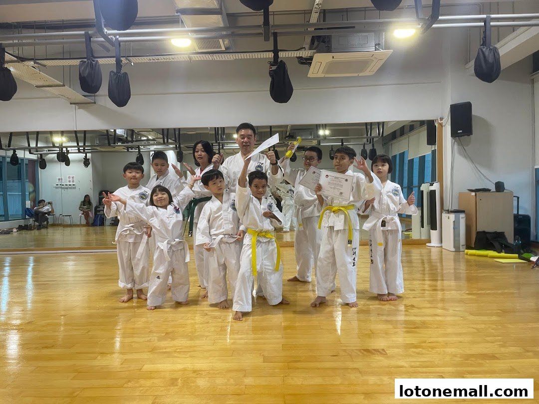 A group of children in martial arts uniforms pose with certificates and yellow belts.
