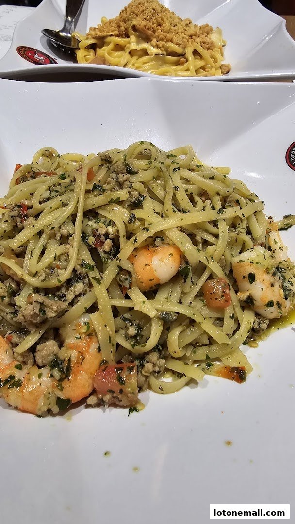 Two plates of pasta, one with shrimp and pesto, the other with a creamy sauce and breadcrumbs.