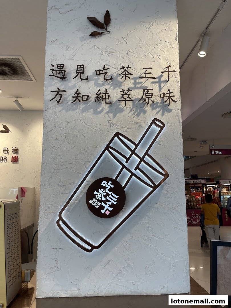A wall with Chinese calligraphy, a stylized cup logo, and a glimpse of a shopping mall interior.
