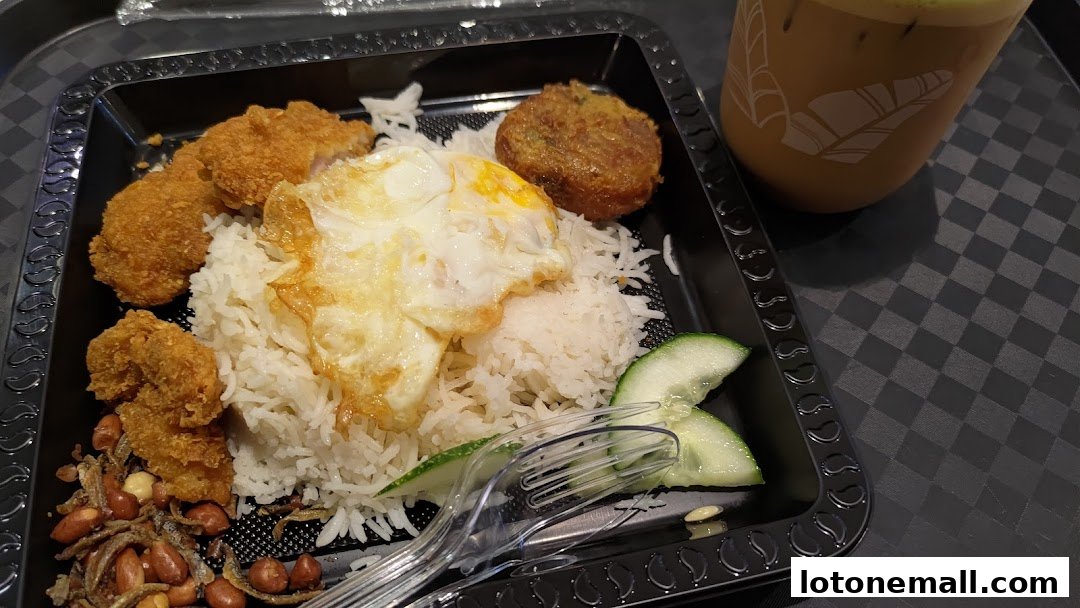 A plate of Nasi Lemak with fried chicken, fried egg, peanuts, anchovies, and cucumber, served with a drink.