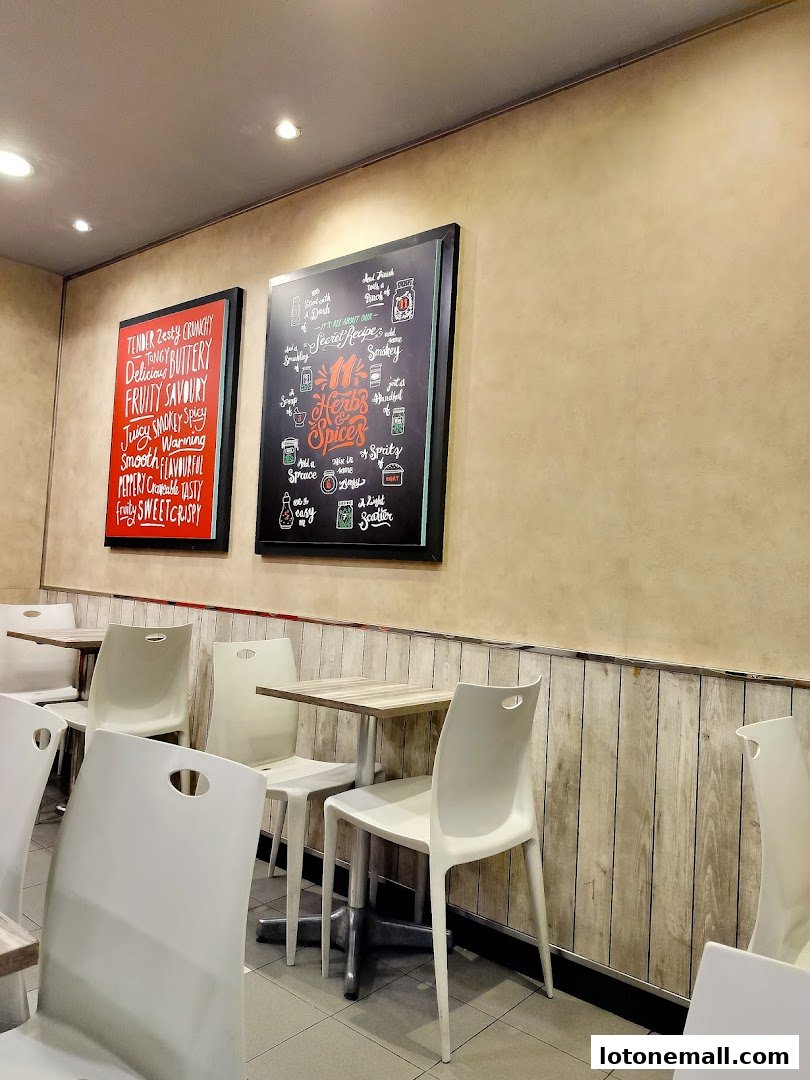 Interior of a KFC restaurant with tables, chairs, and decorative boards on the wall.