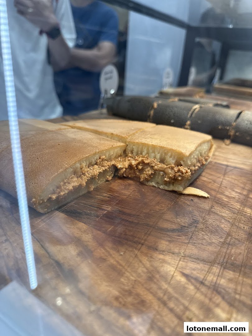 A close-up of a peanut-filled pancake sliced into squares on a wooden surface.