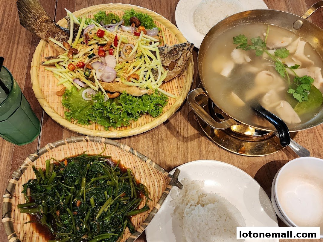 A spread of Thai dishes including fried fish with mango salad, stir-fried vegetables, and soup.