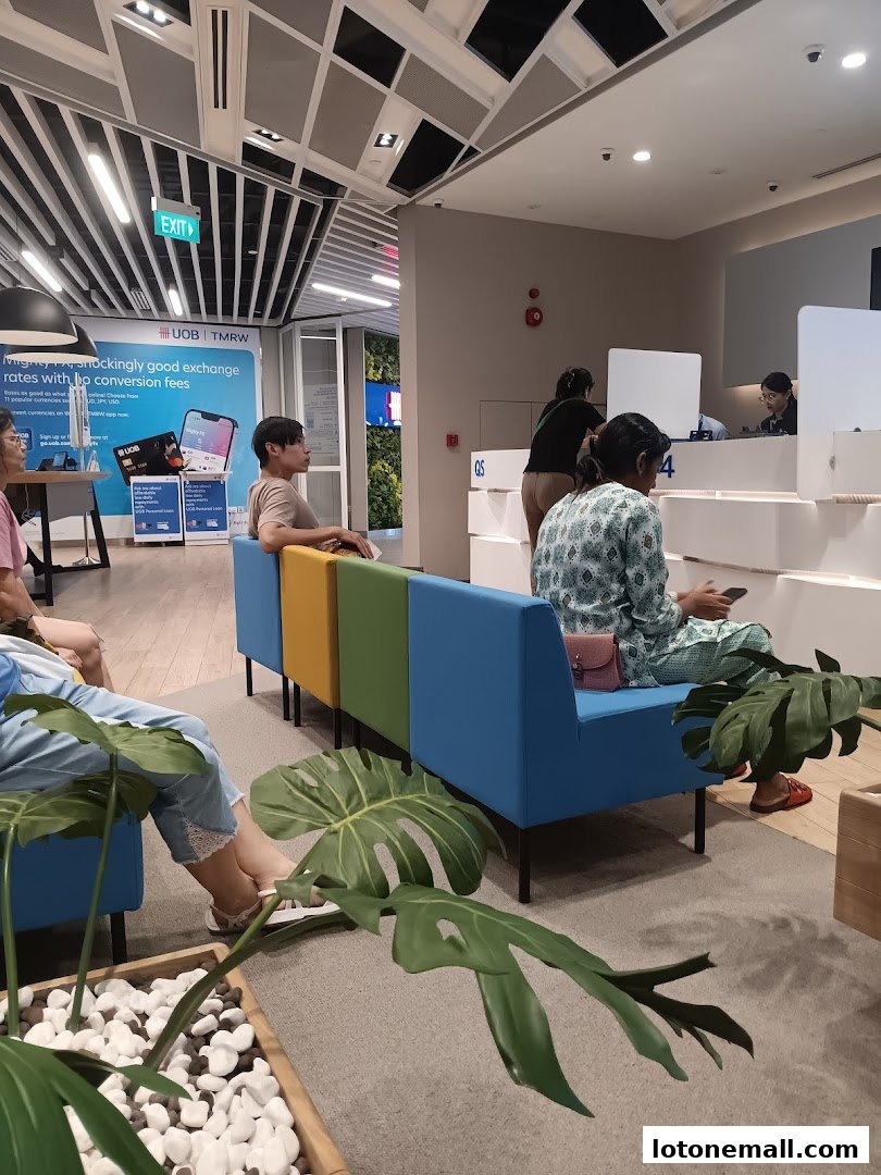 People waiting in a modern bank lobby with colorful seating and greenery.