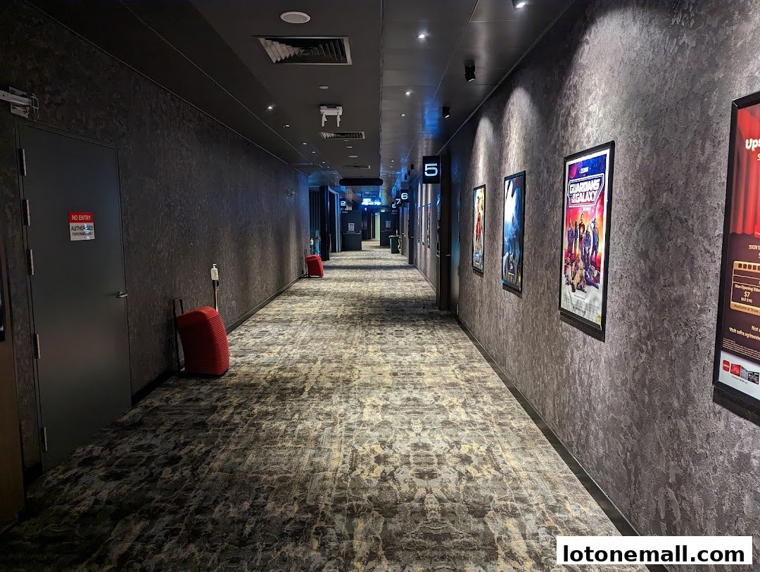 A dimly lit cinema hallway with movie posters and numbered doors.