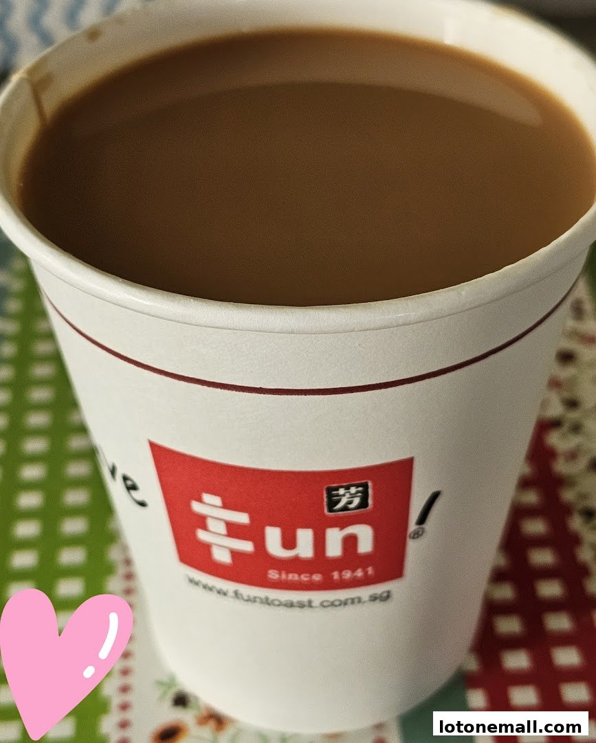 A close-up of a cup of coffee with the Fun Toast logo and a pink heart sticker.