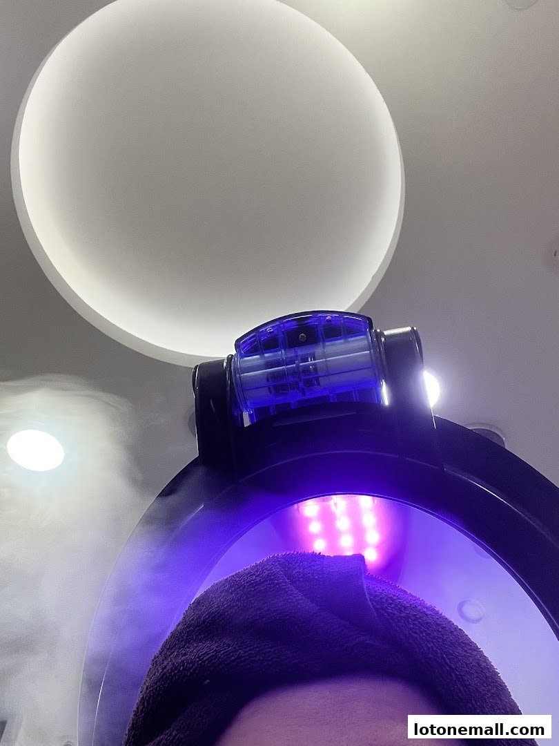 A person's head with a towel, undergoing a steaming hair treatment with purple lights.