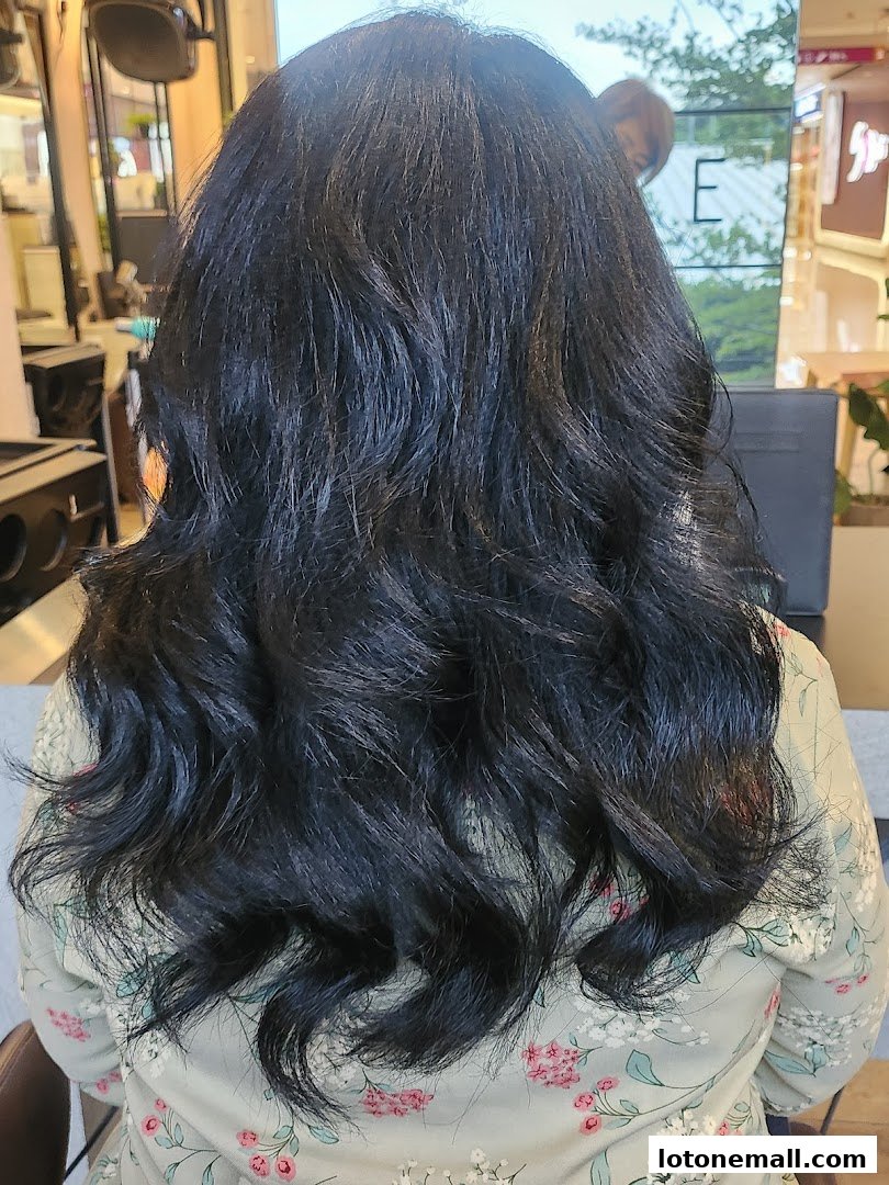 A person with long, dark, wavy hair styled in a salon.