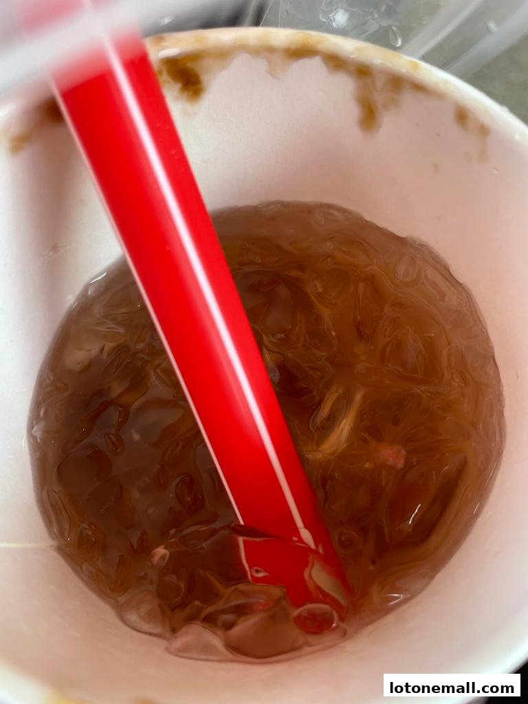 A close-up of a refreshing LiHO TEA beverage with ice and a red straw.