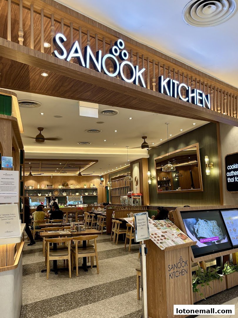Interior view of Sanook Kitchen restaurant with tables, chairs, and a prominent sign.