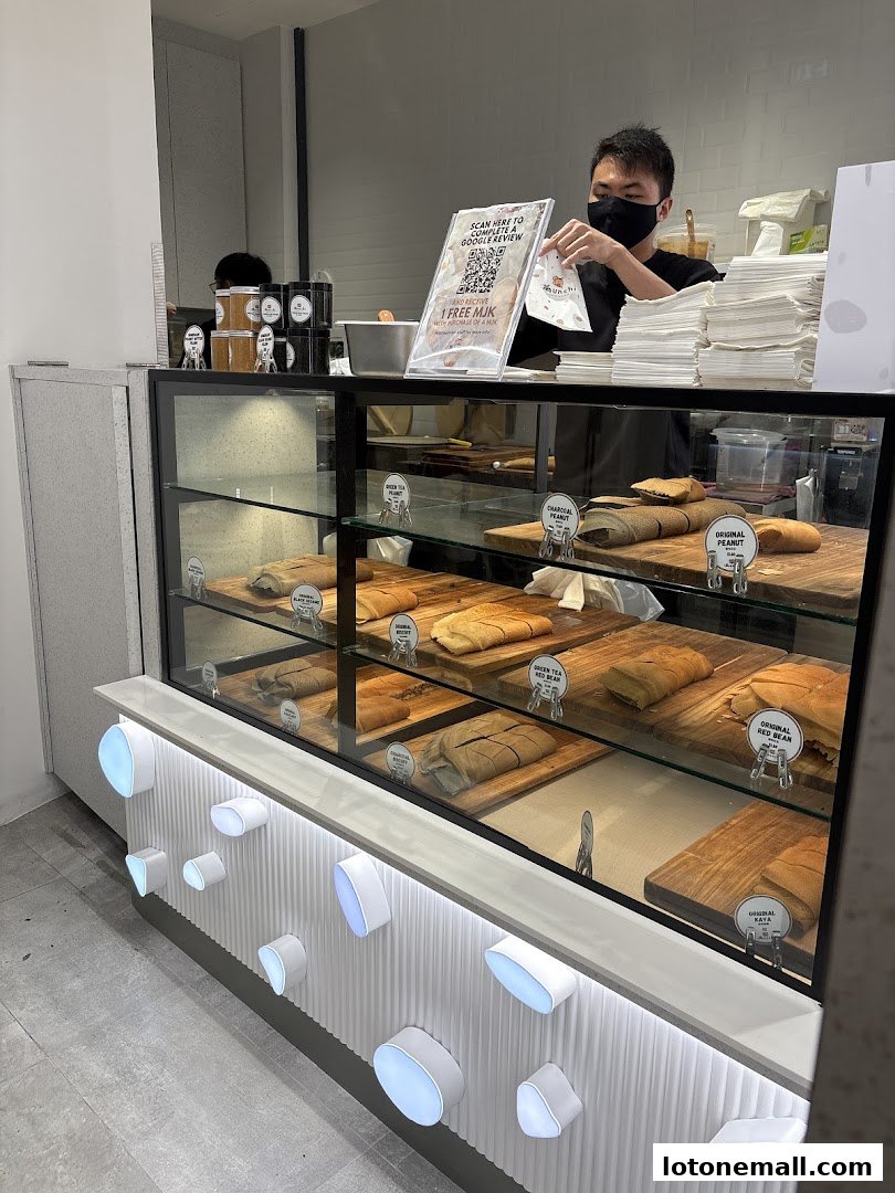 A display case filled with various pancakes at Munchi Pancakes, with a staff member behind the counter.
