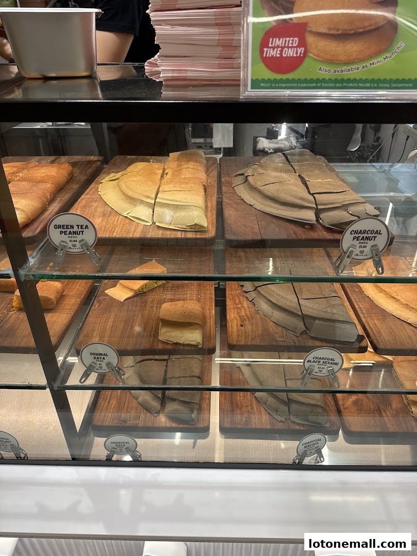 A display case filled with various flavors of pancakes, some sliced and presented on wooden boards.