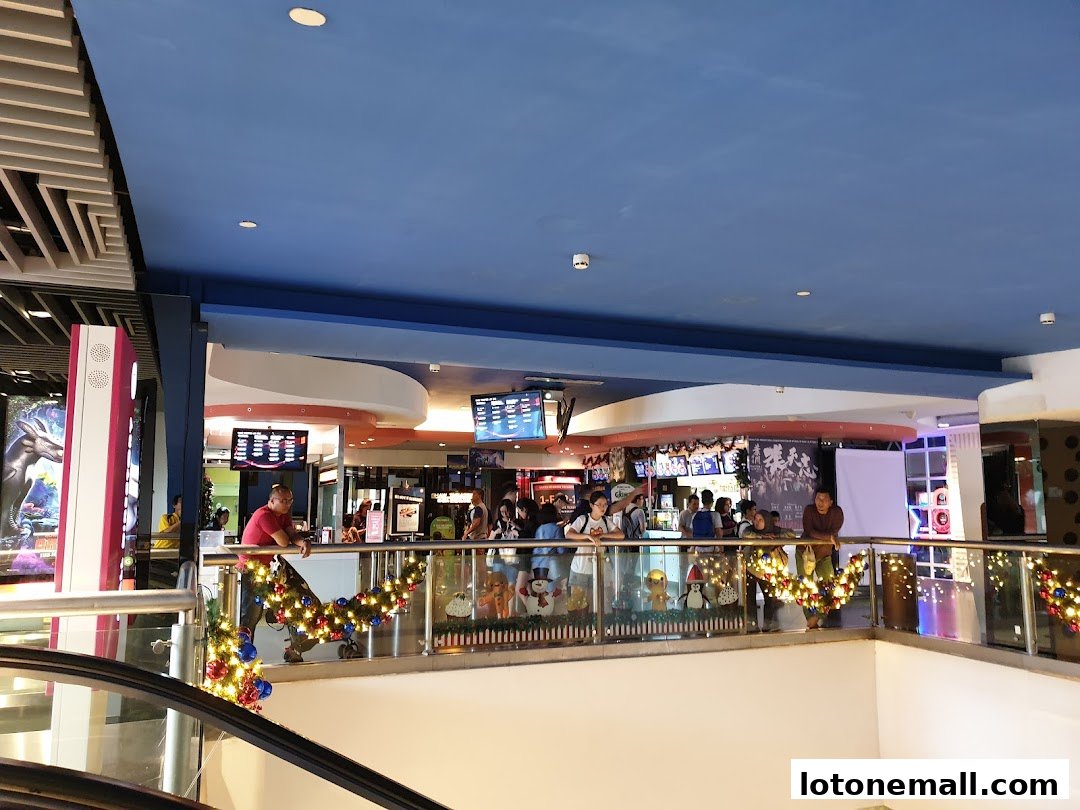 People gathered at a cinema lobby with movie posters and ticket counters visible.