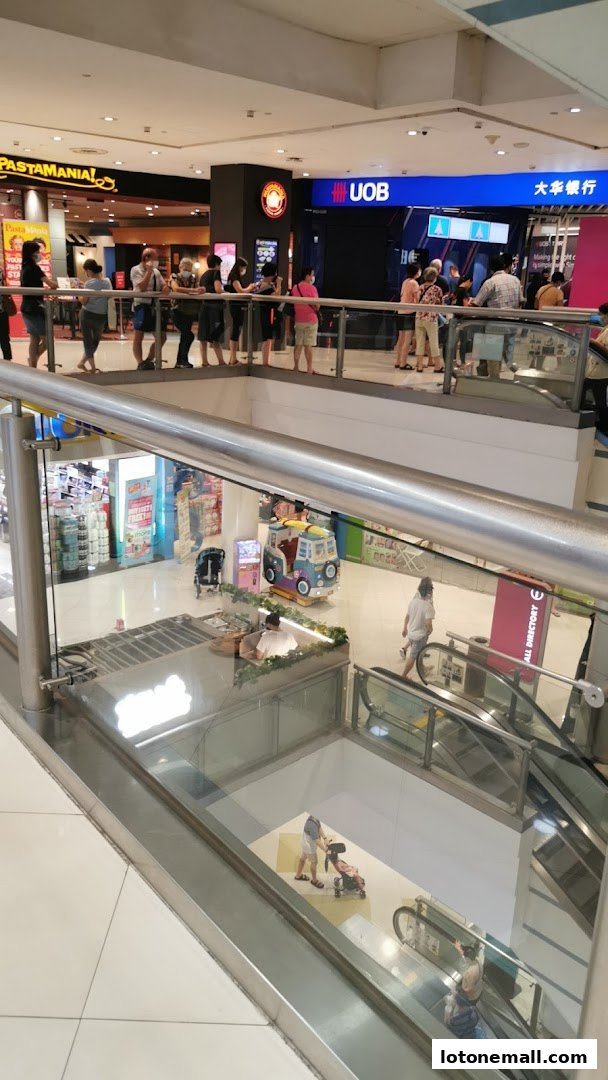 People queuing outside a UOB bank branch and other shops in a mall.