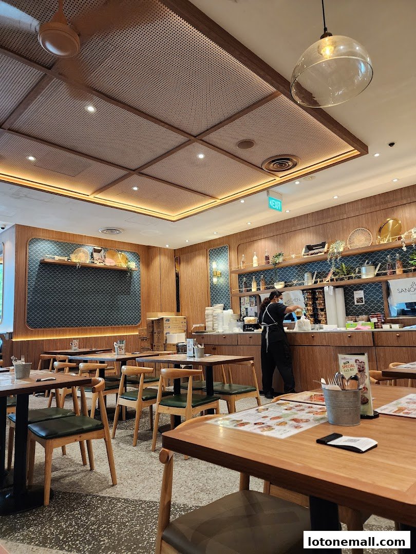 Interior view of Sanook Kitchen with tables, chairs, and a staff member at the counter.