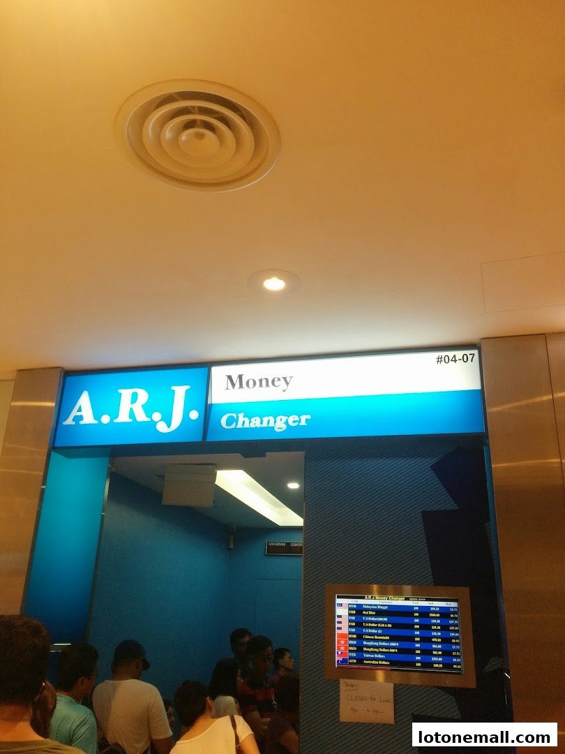The entrance to A.R.J. Money Changer with a digital display showing exchange rates.