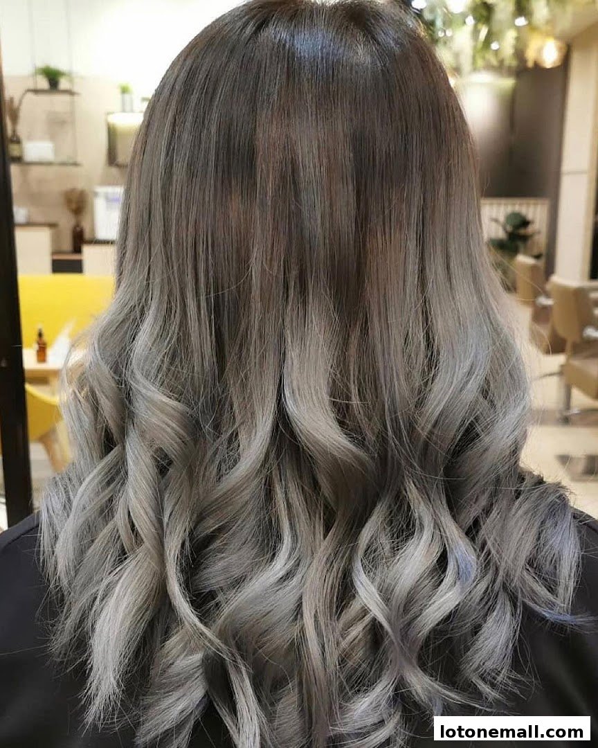 A person's back with beautifully styled, wavy hair featuring a grey ombre color.