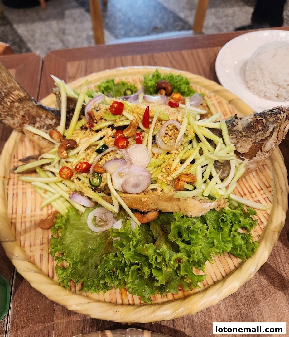 A whole fried fish topped with a fresh mango salad and served with rice.