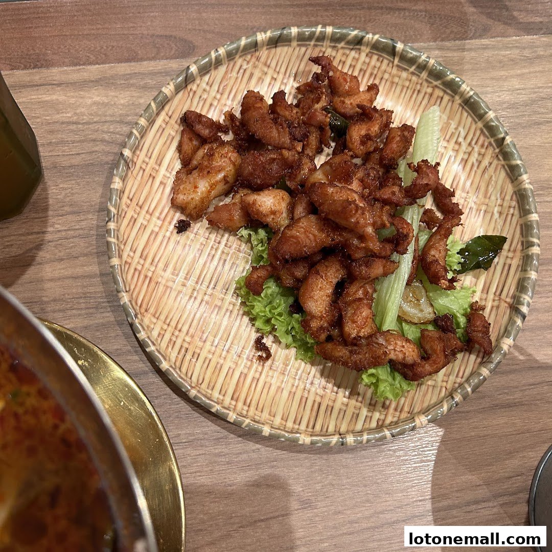 A close-up shot of crispy fried chicken pieces served on a woven platter with lettuce and cucumber.