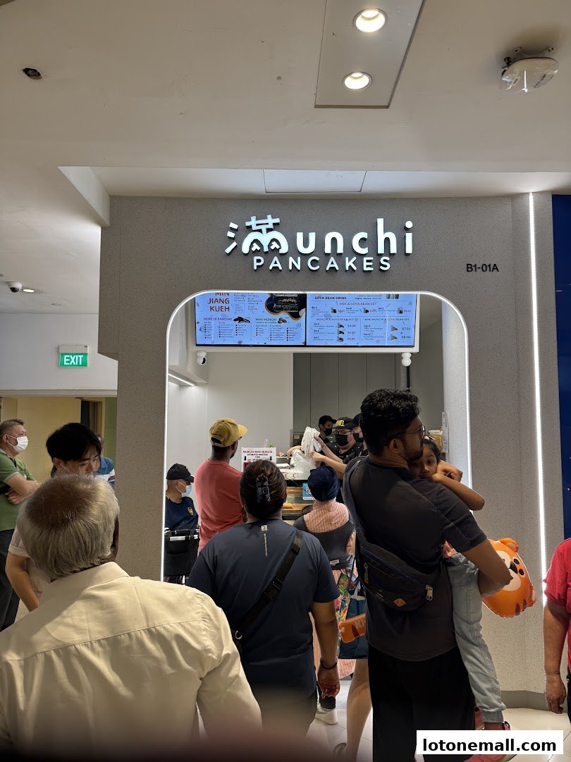 People queuing at Munchi Pancakes shop with a menu displayed.