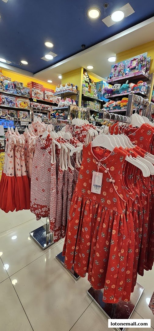 A display of colorful children's dresses and toys in a brightly lit retail store.