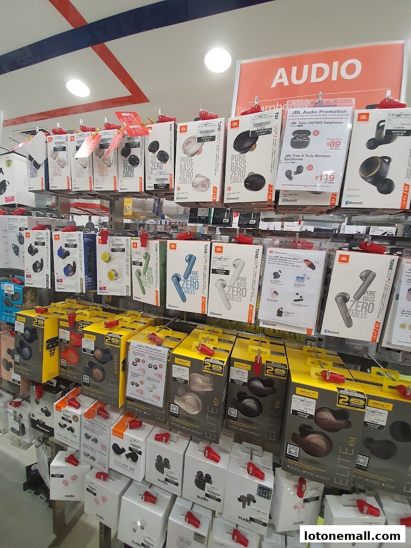 A display of various wireless earphones and audio accessories from brands like JBL and Jabra.