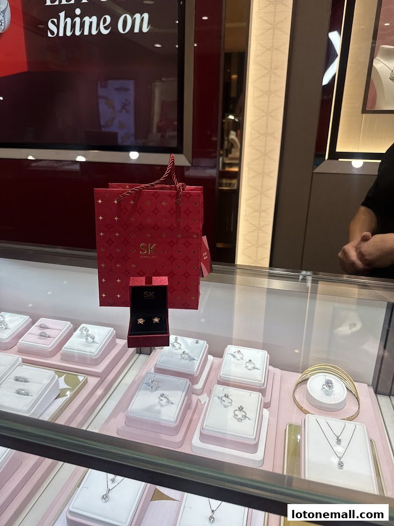 A display case filled with SK Jewellery, featuring rings, earrings, and necklaces.