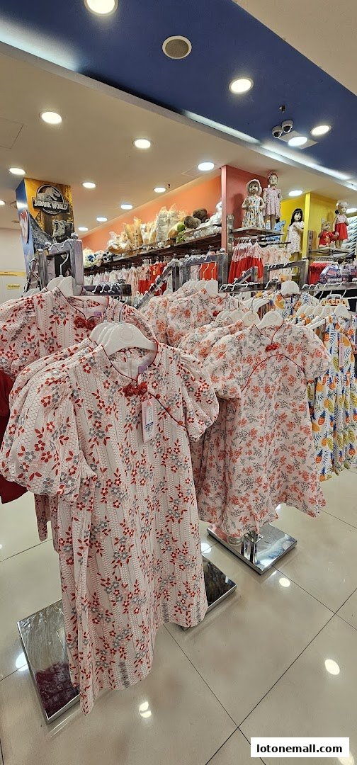 Rows of children's dresses with floral patterns displayed on hangers inside a store.