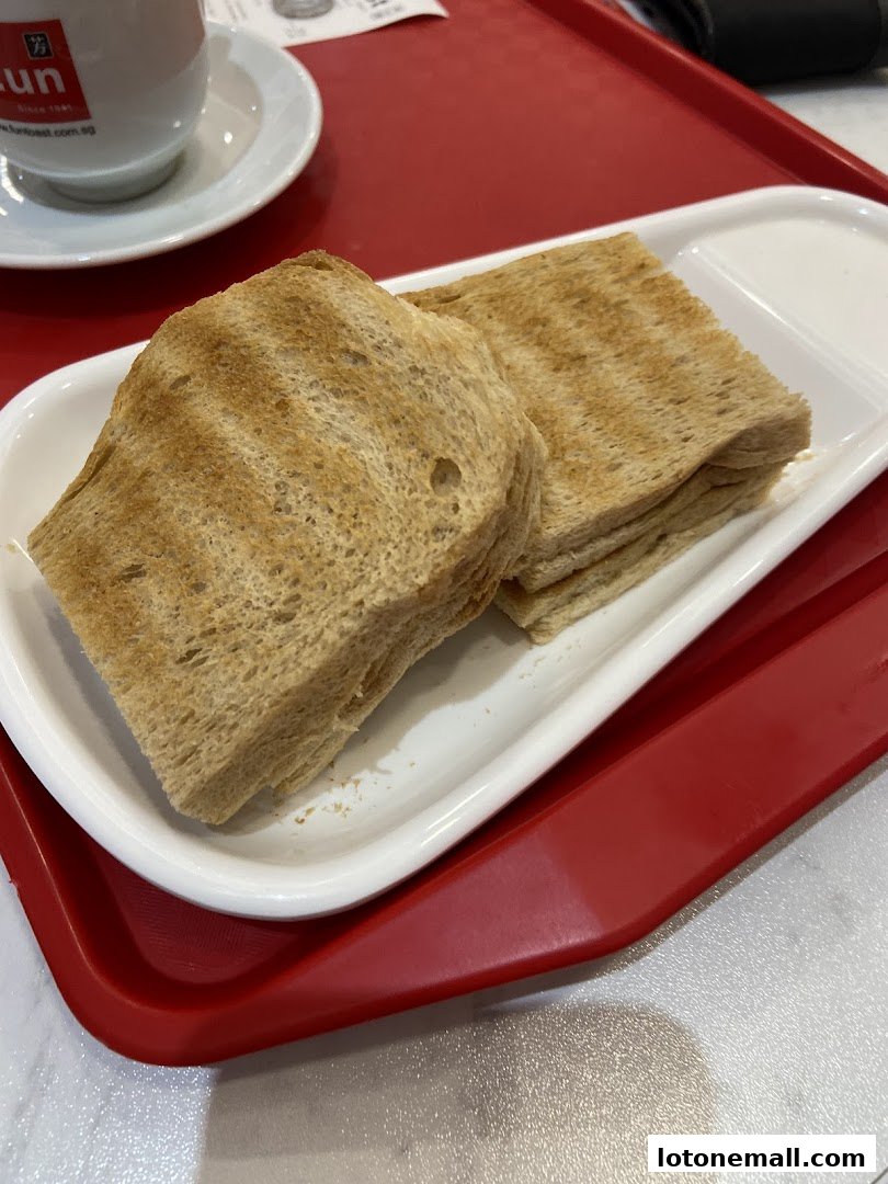 A close-up shot of two servings of toasted bread on a white plate with a cup in the background.