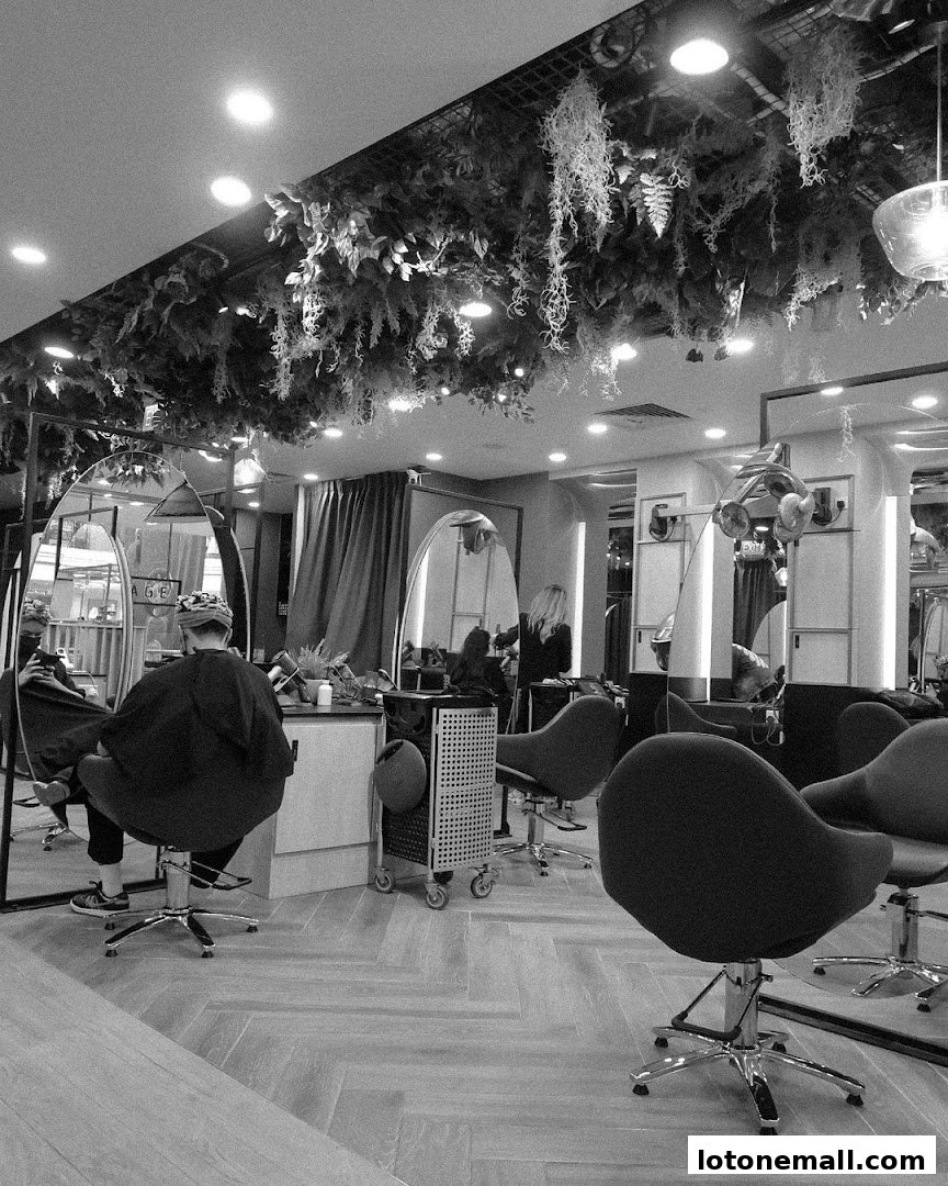 Interior of a modern hair salon with styling chairs, mirrors, and lush ceiling greenery.