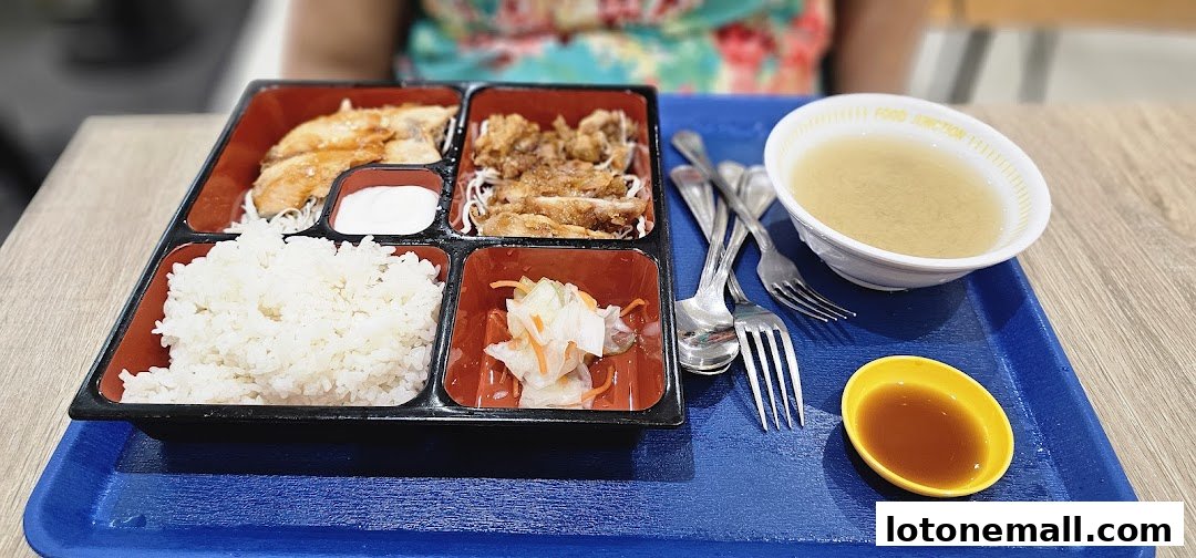 A bento box meal with rice, chicken, and soup is served on a blue tray.