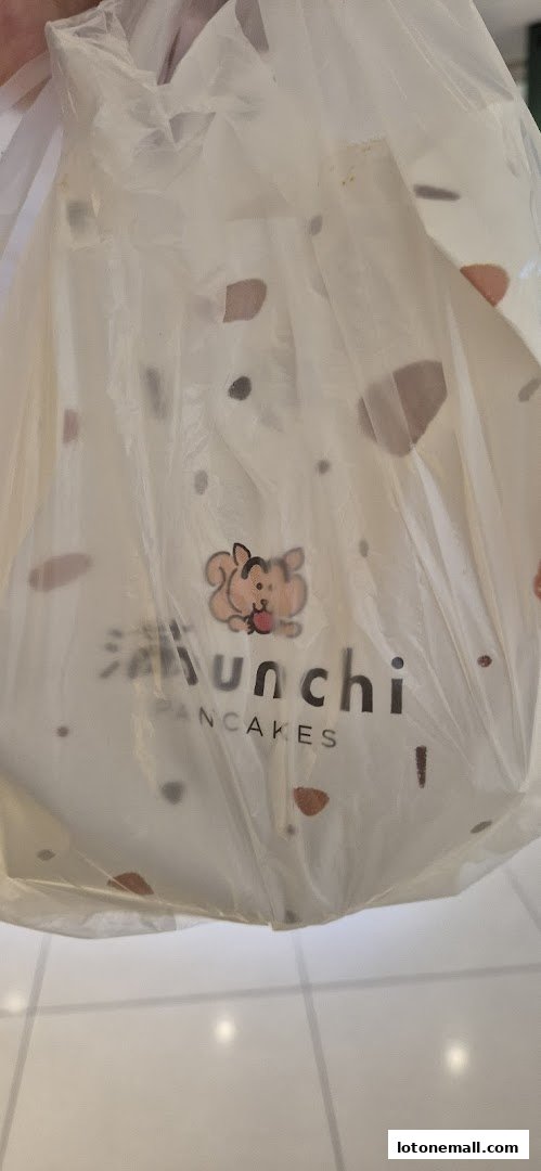 A white plastic bag with the Munchi Pancakes logo and a cartoon squirrel.
