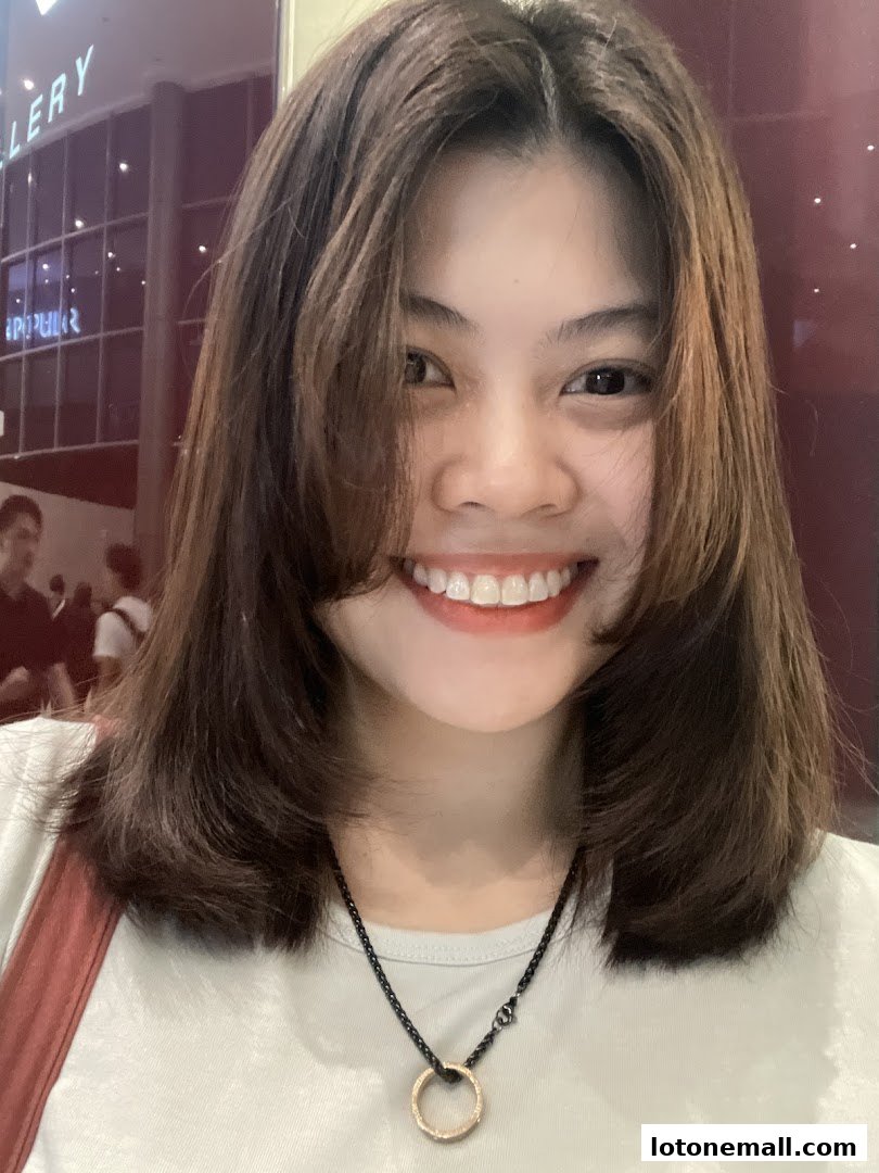 A young woman with a bright smile and stylish haircut poses for a selfie.