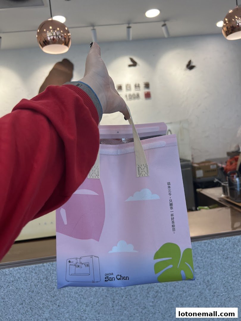 A person holds a pink shopping bag from CHICHA San Chen with a tea-making illustration.